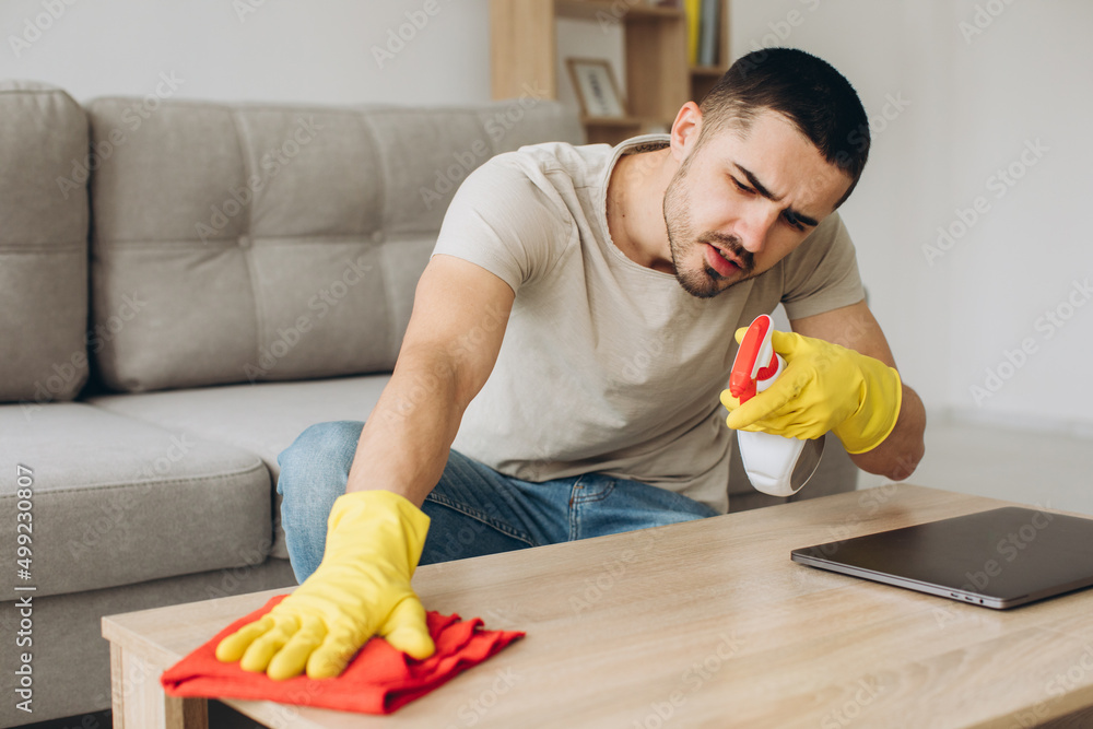 A young man cleans the living room at home, wipes the table. A young man cleans the living room at home, wipes the table.