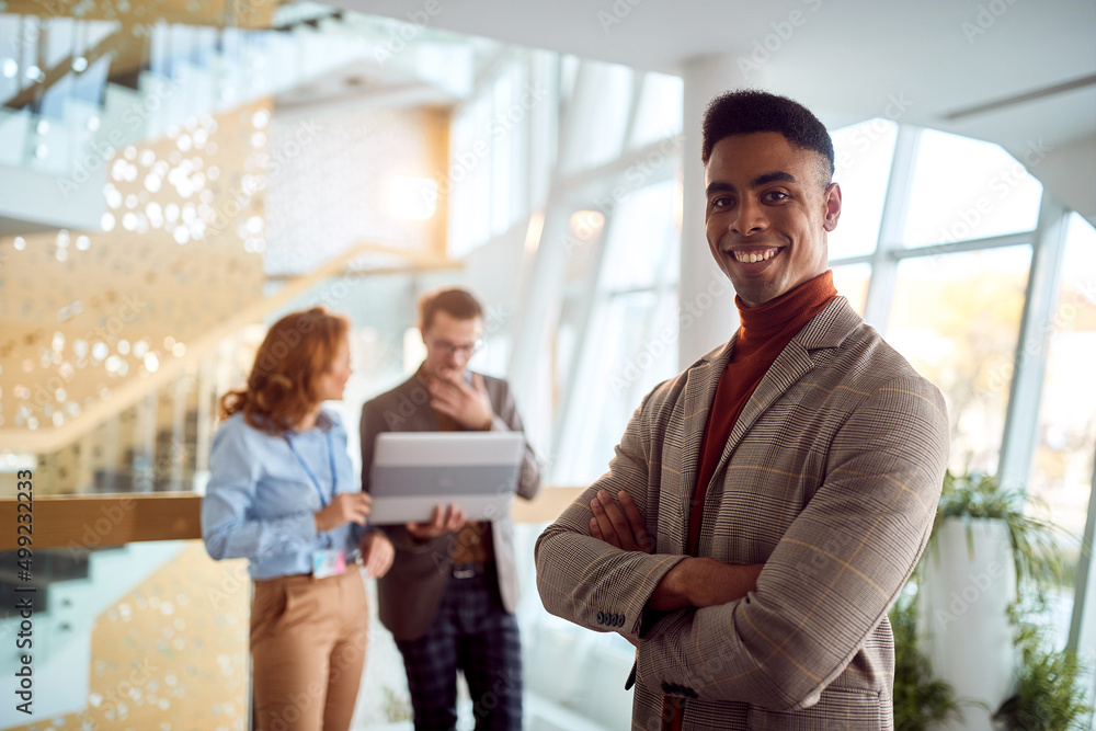 Young businessman is posing for a photo while standing in company building hallway. Business, people, company Young businessman is posing for a photo while standing in company building hallway. Business, people, company