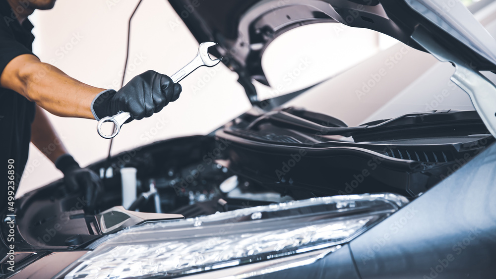 Close-up hand auto mechanic using the wrench to repairing car engine problem. Concepts of check and fix car and maintenance servicing.