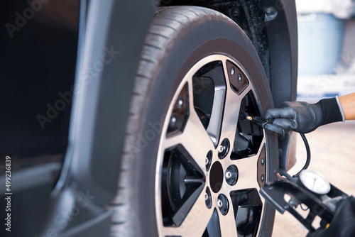 Auto mechanic checking air pressure and inflating car tires. Concept of car care service and maintenance or fix the car leaky or flat tire.