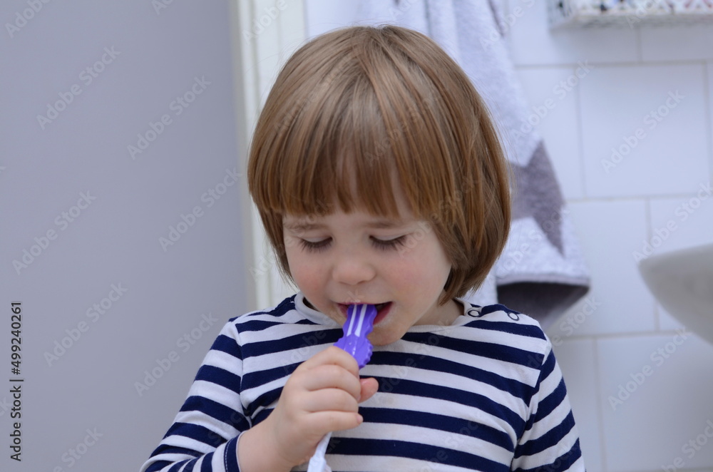 Little blond boy learning brushing his teeth in domestic bath. Kid learning how to stay healthy. Health care concept. Little blond boy learning brushing his teeth in domestic bath. Kid learning how to stay healthy. Health care concept.