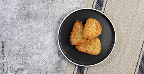 Traditional Hash brown potato fried pancakes on a round plate on a dark gray background. Top view, flat lay