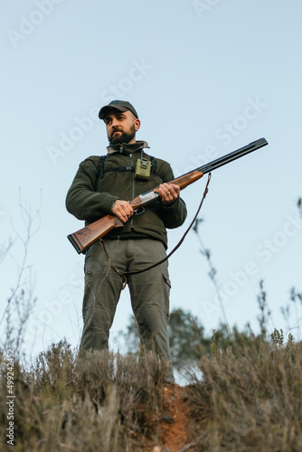 Man with gun hunting in countryside in clear day