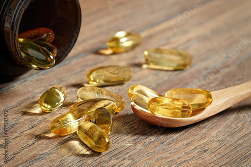 Closeup of a lot of omega 3 oil capsules and a wooden spoon.