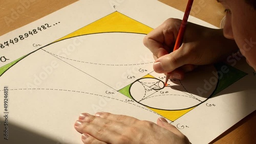 Young mathematician and designer Pavel Kubarkov drawing golden spiral on the paper. Date of shooting day 24 March 2022 year, MSK time. This video was filmed in Russia. photo