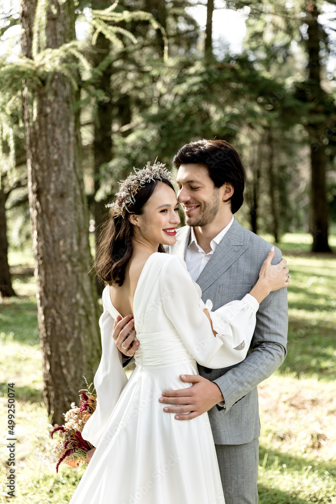 Happy newlywed couple smiling and hugging in the forest Happy newlywed couple smiling and hugging in the forest