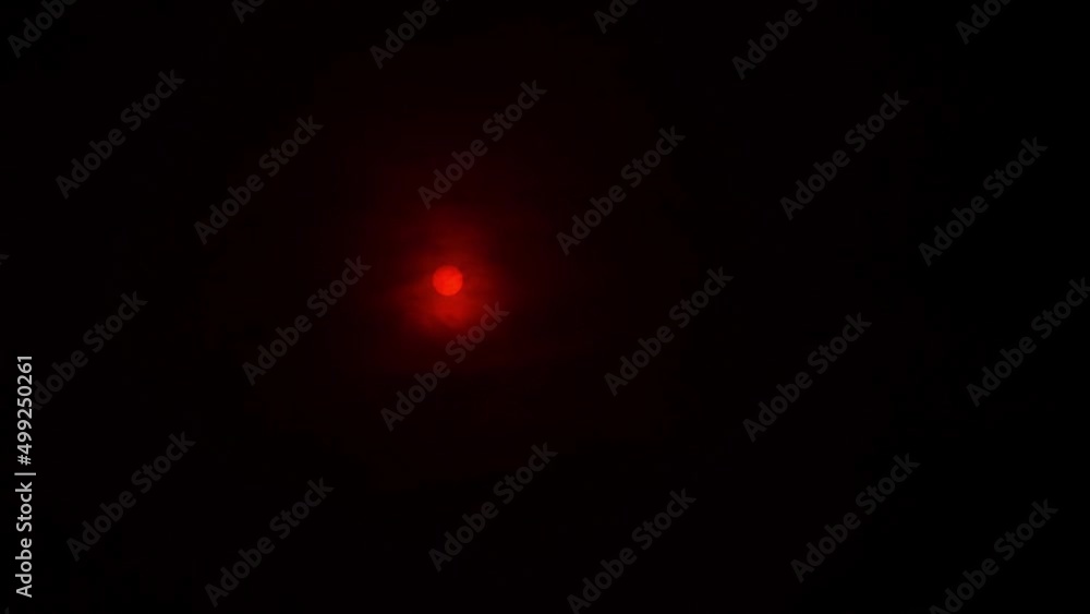 Bright red-orange sun in the black sky, filmed through a sun filter with lens flare Bright red-orange sun in the black sky, filmed through a sun filter with lens flare