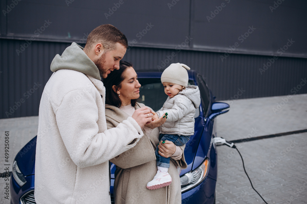 A young, happy family charges an electric car