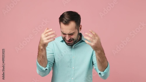 Sad upset worried disturb young brunet man 20s wears blue shirt sigh suspire sithe put spreading hands ask scream why isolated on plain plain pink background studio. People emotions lifestyle concept photo