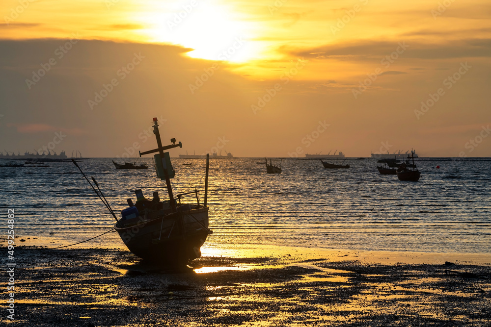 Silhouette wooden fishing boat on beach at sunset, Sriracha