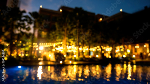 Blurred wedding party in outdoor garden by the pool. Light up decor