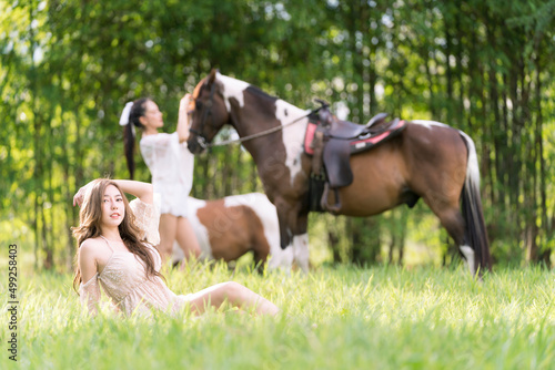Beautiful woman and horse in the field at spring. Happy woman in white dress with horse in summer field forest. © Thirawatana