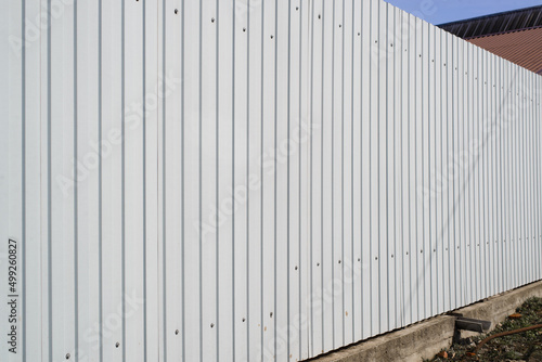 Building material fence of gray corrugated metal profile outdoors. Perspective view