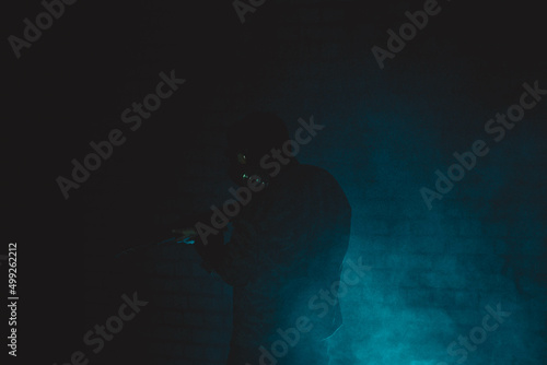 A man in a gas mask with a machine gun, a photo in a dark room