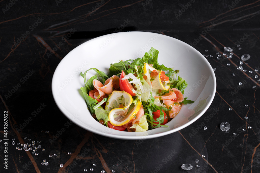 Salad with shrimps, vegetables and herbs in a white plate on a black background Salad with shrimps, vegetables and herbs in a white plate on a black background