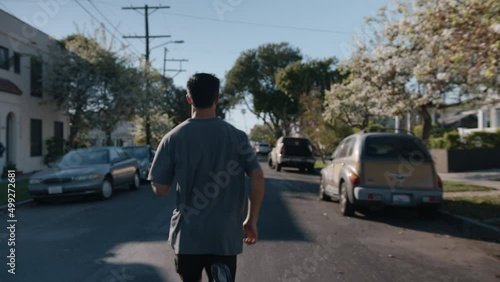 Wallpaper Mural Young confident male sportsman runner shot moving outside on asphalt road in green town, countryside between parking cars, trees and buildings at daytime. Healthy lifestyle concept of self training Torontodigital.ca
