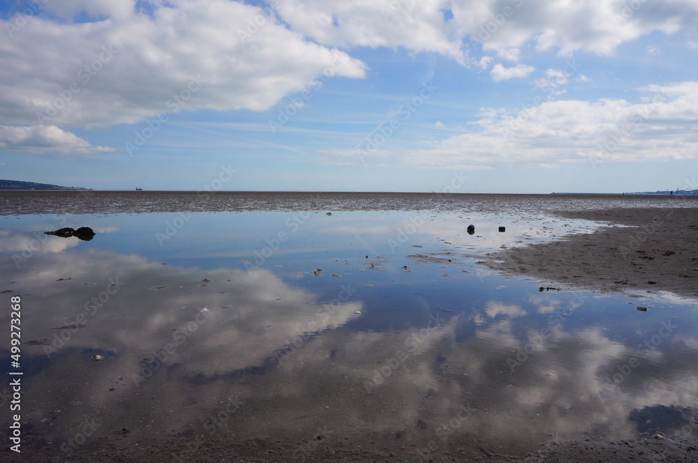 A mirror-like reflection of clouds on the seashore.