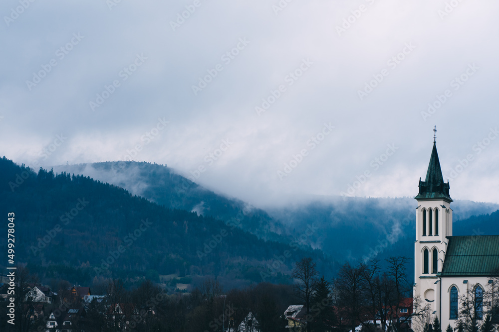 church in the Polish city of Mszana Dolna against the mountains and clouds - obrazy, fototapety, plakaty 