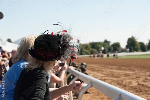 Woman watching horse race at race track with big fancy hat Fototapet