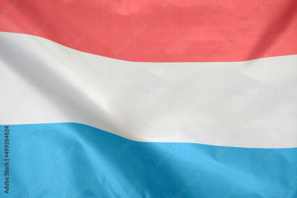 Fabric texture flag of Luxembourg. Flag of Luxembourg waving in the wind. Luxembourg flag is depicted on a sports cloth fabric with many folds. Sport team banner Fabric texture flag of Luxembourg. Flag of Luxembourg waving in the wind. Luxembourg flag is depicted on a sports cloth fabric with many folds. Sport team banner