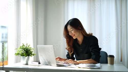 Attractive smart asian female adult using laptop computer working online from home at living room with cheerful freshness expression casual happiness lifestyle