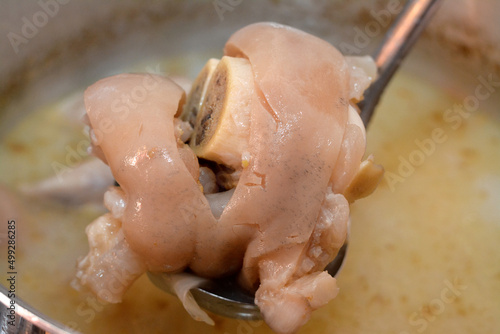 Selective focus of an Arabic Egyptian cuisine of kawareh soup ( trotters soup ) that is full of collagen and Gelatin, cooked cow feet in a cooking pot with onion, cow boneless trotters with its soup photo