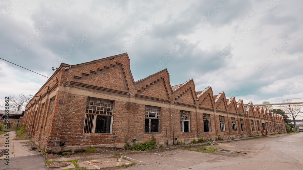 Old industrial warehouse in Kragujevac, Serbia, made of red bricks. Ruined windows and deserted interior on a cloudy day with picturesque skies.