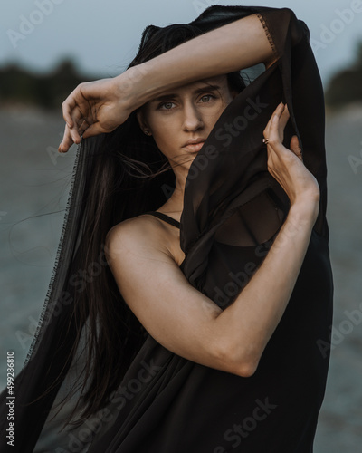 Portrait of the young woman covered flying black fabric © Elena Odareeva