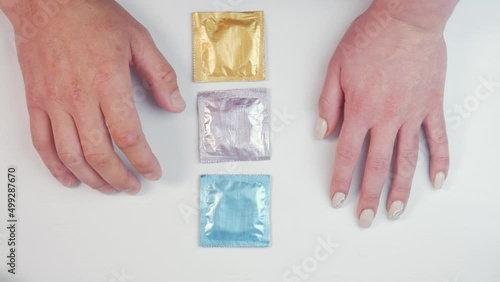 Male and female hands pick up multi-colored condoms on a white background