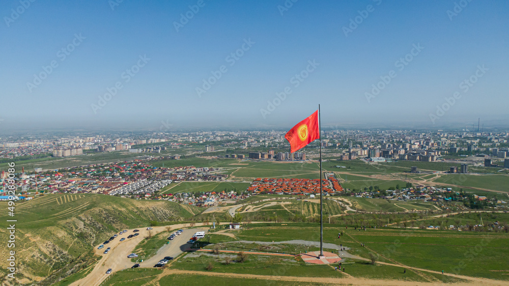 Aerial view of Bishkek city from the mountains. Flagpole with Kyrgyzstan flag