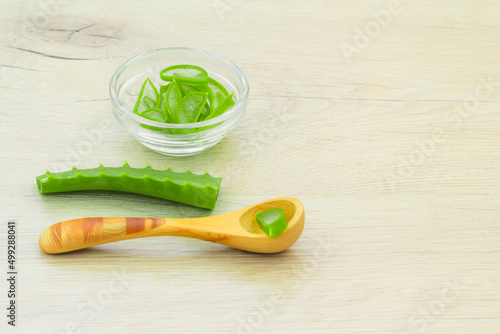 aloe vera slice top view texture background. wooden spoon, aloe leaves, glass bowl with chopped leaves