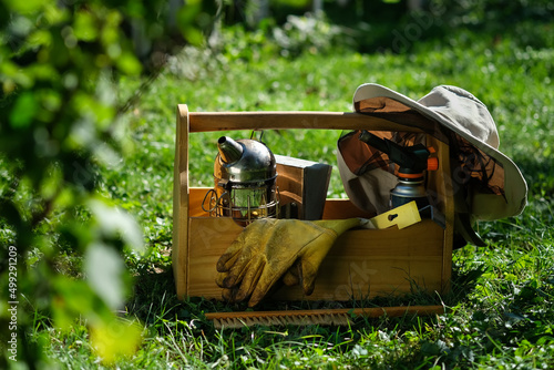 A tool of the beekeeper. Everything for a beekeeper to work with bees. Smoker, a chisel, a box, beekeeper suit for protection from the bees. Beekeeping equipment. Photo on the topic of beekeeping.