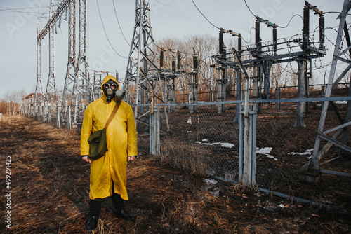 male worker standing on territory of power station. Environmentalist wearing protective uniform, gas mask.
