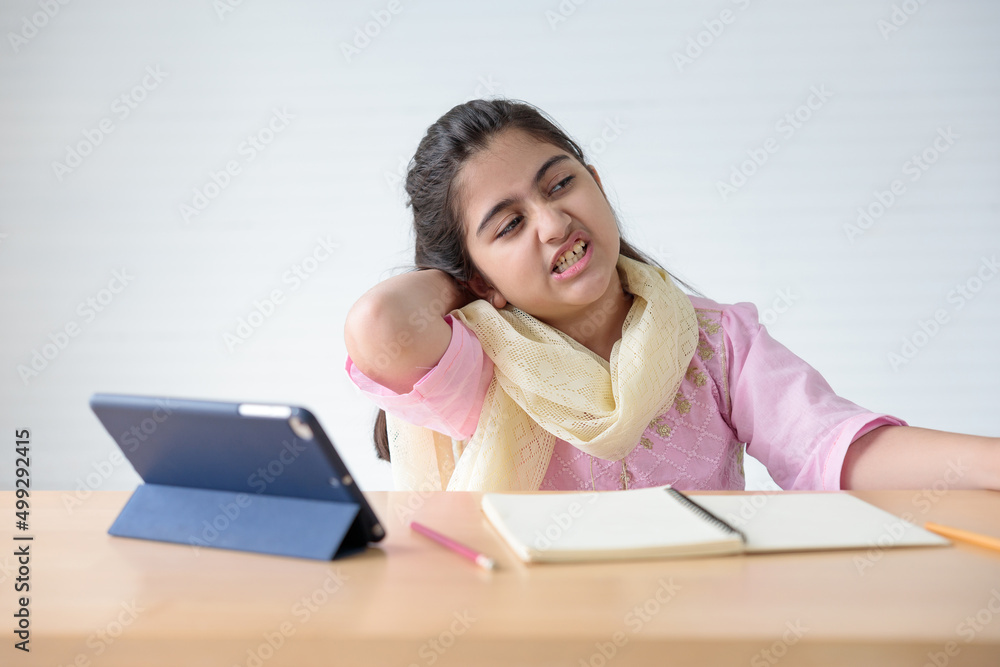cute Indian girl feeling neck pain after finished online learning class, education concept cute Indian girl feeling neck pain after finished online learning class, education concept