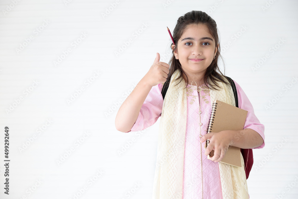 cute Indian girl holding notebook for learning and thumbs up pose, education concept cute Indian girl holding notebook for learning and thumbs up pose, education concept