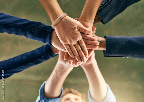 Lets get further together. Closeup shot of a group of people joining their hands in a huddle.