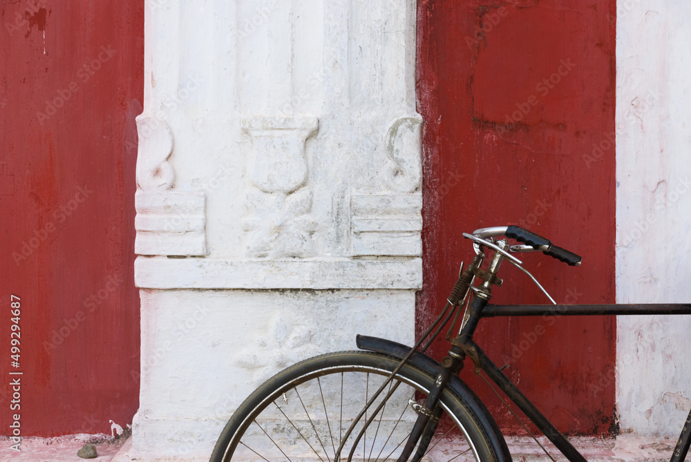 Closeup of old rusty bicycle leaning on the wall of a hindu temple