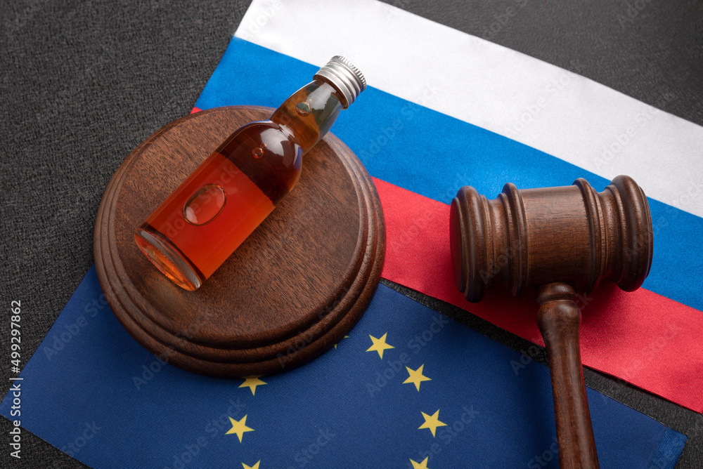 Bottle of alcohol and judge gavel on Russia and European Union flags. Alcohol smuggling.