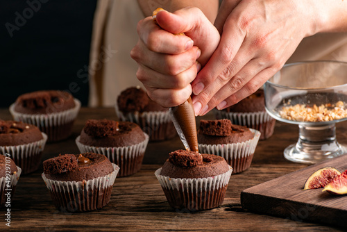 Process of making muffins. Chef fills the cupcakes with chocolate cream from the confectionery bag.
