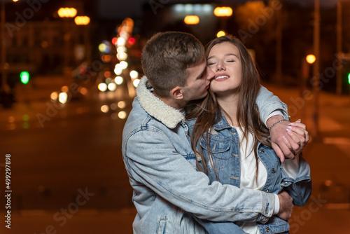 Guy gently hugs and kisses his girlfriend on evening city background. Romantic date. © somemeans