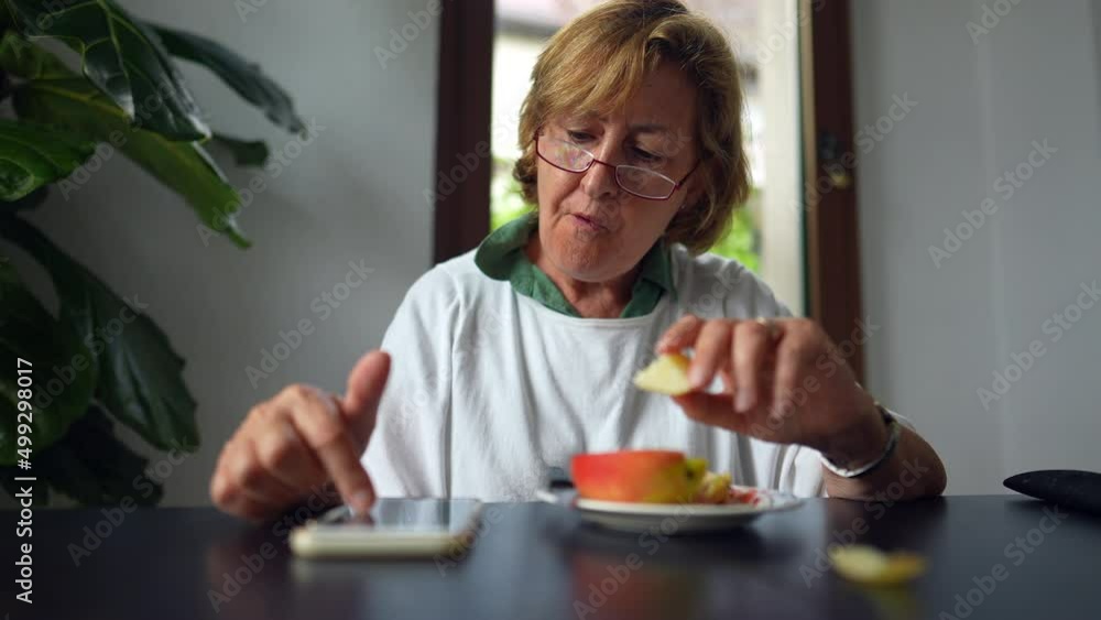 An older woman using technology and eating 70s person browsing internet An older woman using technology and eating 70s person browsing internet