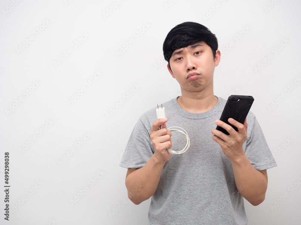 Man holding cable charging mobile with smartphone bored emotion copy space Man holding cable charging mobile with smartphone bored emotion copy space