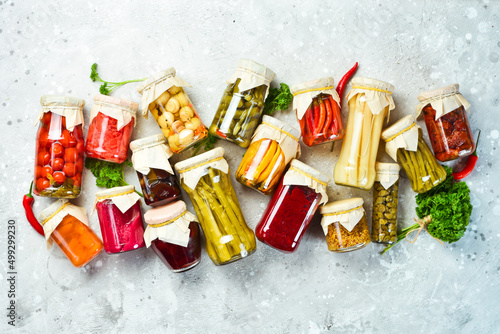 Jars with various pickled vegetables on a stone background. On a stone background. Top view.