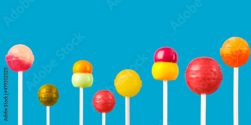 Multi-colored candies on a stick, blue background.Many colorful lollipops (Chyupa-Chyups) on a blue background
