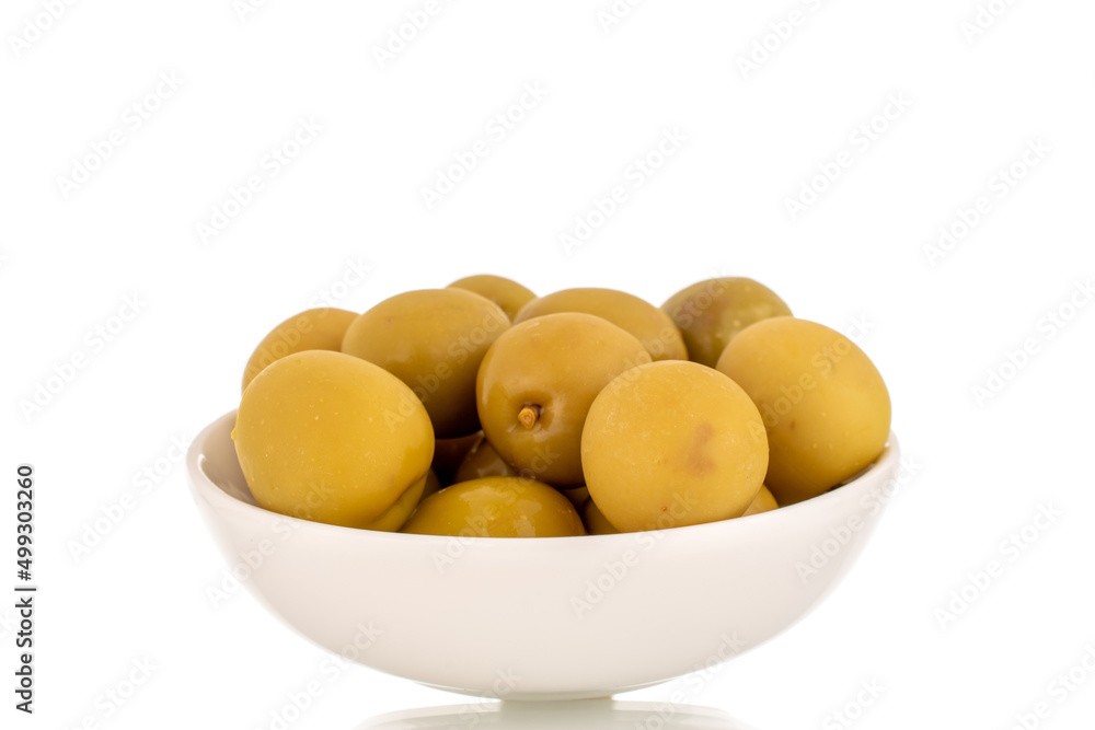 Several green pitted olives in a ceramic saucer, macro, isolated on white.
