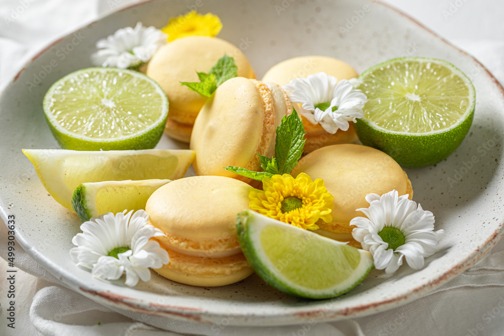 Delicious and fresh lemon macaroons with spring flowers on plate. Delicious and fresh lemon macaroons with spring flowers on plate.