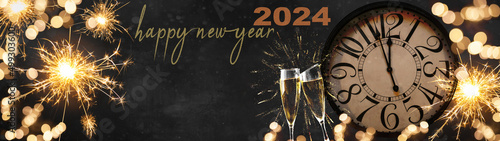 HAPPY NEW YEAR 2024 - Festive silvester New Year s Eve Party celebration background panorama banner long - Golden yellow fireworks  sparklers  clock and champagne classes toasting in dark black night