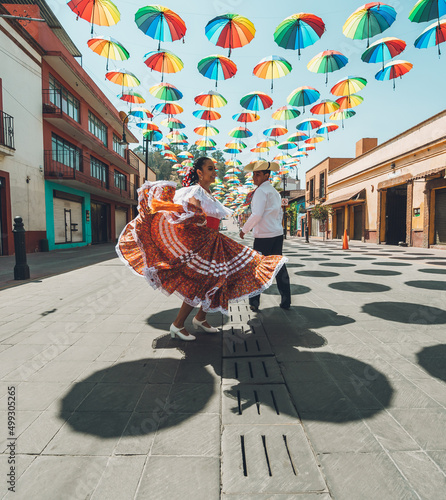 Dancers of typical Mexican dances from the central region of Mexico, doing their performance in the street adorned with colored umbrellas.
