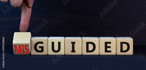 Guided or misguided symbol. Turned wooden cubes and changed the concept word Misguided to Guided. Beautiful grey table grey background, copy space. Business and guided or misguided concept.