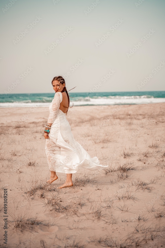 Model in boho style in a white long dress and silver jewelry on the beach. Her hair is braided, and there are many bracelets on her arms. Model in boho style in a white long dress and silver jewelry on the beach. Her hair is braided, and there are many bracelets on her arms.